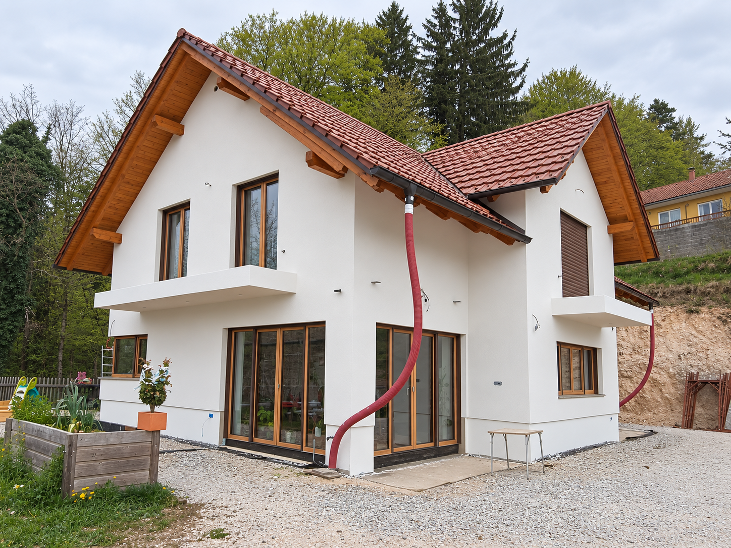 Hiša z belo fasado in rdečo streho na pobočju